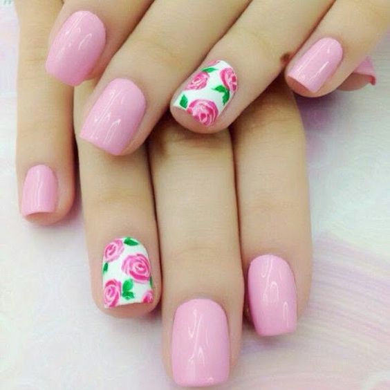 Dos manos con uñas de color rosa y dibujos de rosas en los dedos anulares