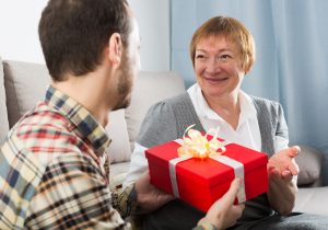 Un hombre joven le da un regalo de cumpleaños a su madre