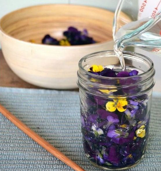 Una jarra vierte solución con glicerina en un frasco lleno de flores